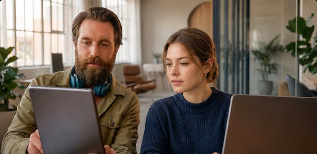 Two colleagues reviewing work on a laptop