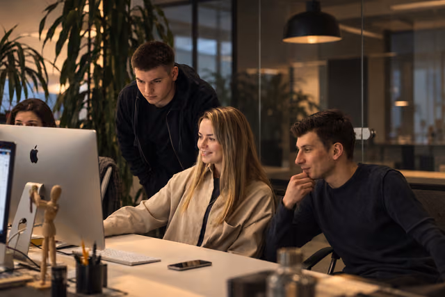 Three colleagues collaborating at a desktop screen